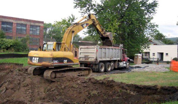 Backhoe loading dirt into dump truck bucket