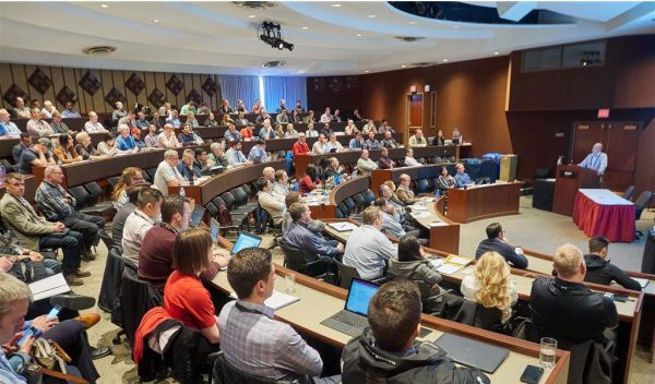 People in a room listening to a person presenting