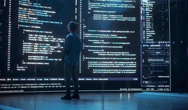 Female operator looking at code on a large digital screen.