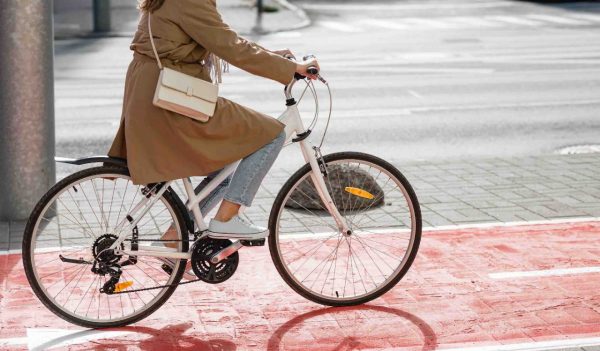 woman cycling along red bike lane road in city