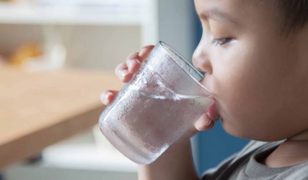 Close-up of a young boy drinking water from a glass.