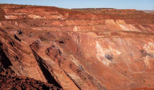 Active deep pit of red iron ore mine in Pilbara region in Western Australia with shadows of various levels