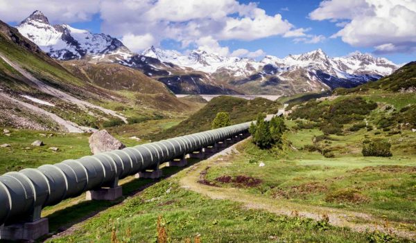 Above ground pipeline running through a valley with the montains in the background.