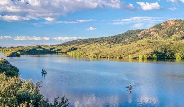Summer morning on  Horsetooth Reservoir at foothills of Rocky Mountains in northern Colorado with a fishing boat and a stand up paddler, popular recreation destination in Fort Collins area