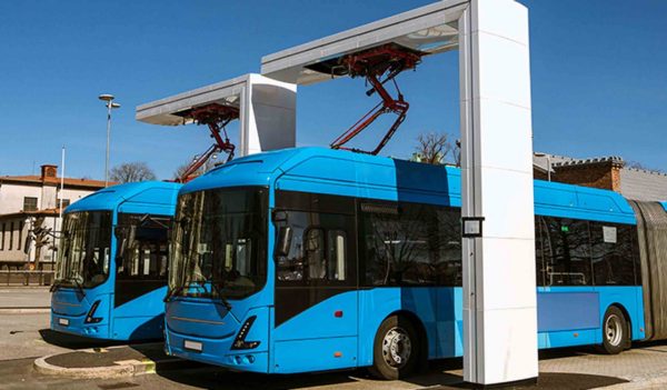 Two blue electric buses at  a charging station. 