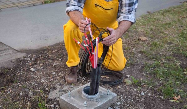 Worker installing optic fiber cables for internet and telephone, power lines installation at street