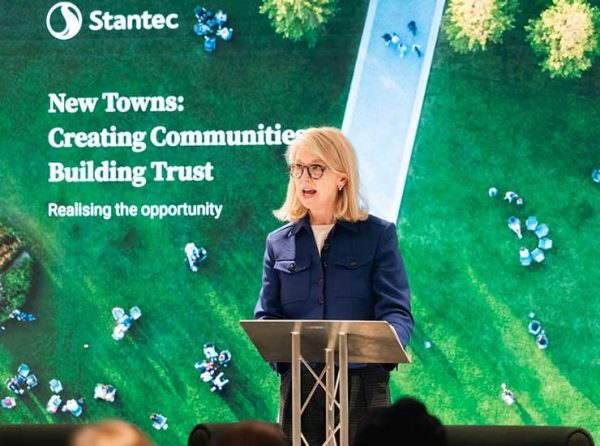 Nancy Macdonald standing at a podium deliverig a speach with Stantec branded graphics in the background.