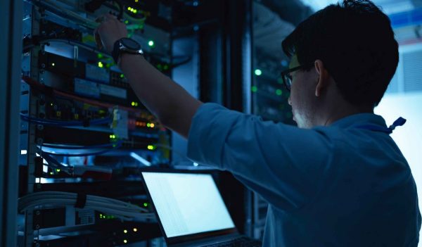 Computer engineer is setting up network in server room,Systems Maintenance Technician,Male engineer working in server room at modern data center