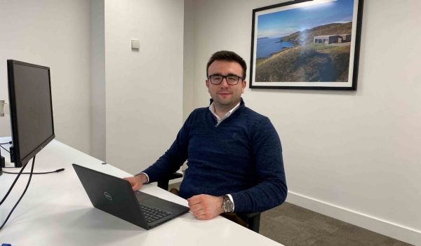 Aaron Doidge sitting at a desk with his laptop in front of him.