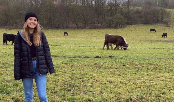 Chloe Joseph standing in a field with cows grazing in the background.