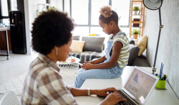 Woman working at her computer with a child sitting nearby.