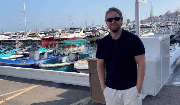 David McVeigh standing on a dock with rows of boatsin the background. 