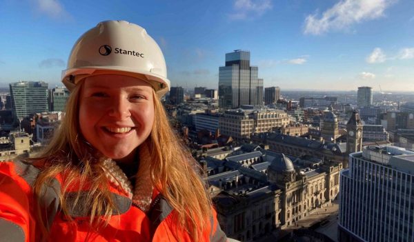 Lauren Wright, wearing a Stantec hard had and safety jacket with the city skyline in the background.