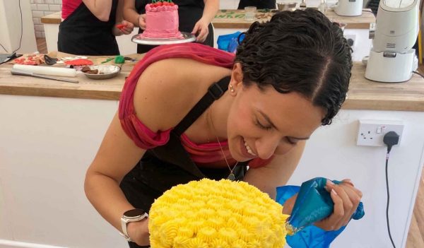 Close-up of Safa Ghanem piping yellow icing ont a cake.