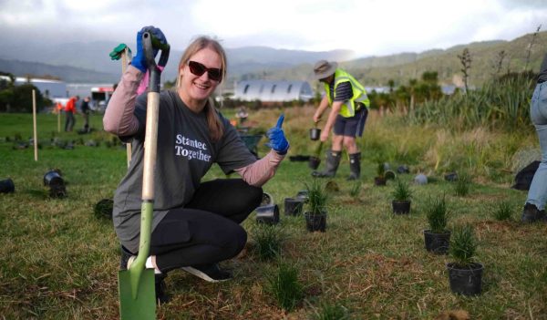 Anna Gibbs kneeling down with a shovel planting trees.