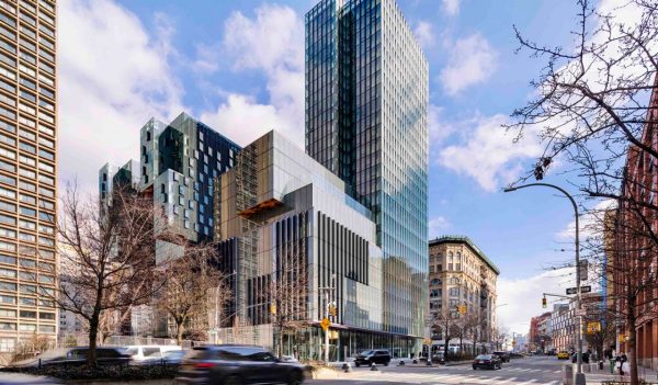 Exterior image of tall glass building from the street, surrounded by lower, brick buildings.