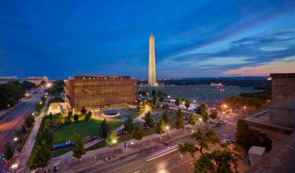 View of the museum at night with the Washington monument in the background. 