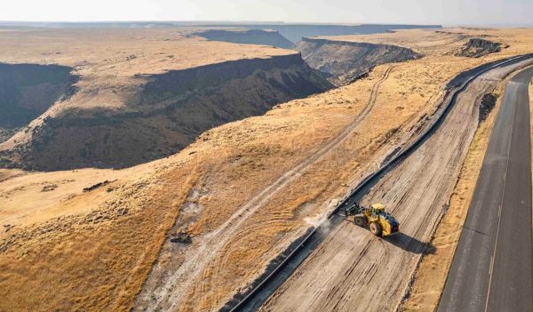 Aerial view of construction equipment working the land beside a road