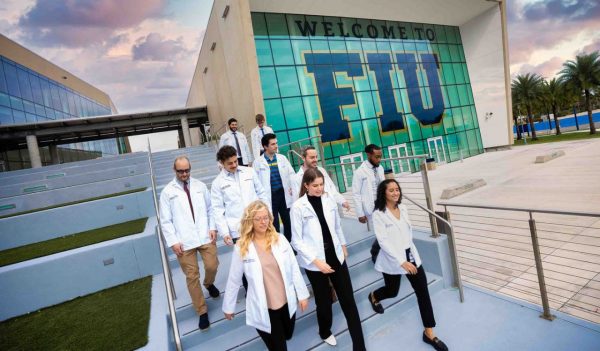 A group of walking walking down stairs outside a building with signage Welcome to FIU