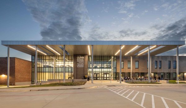 Exterior of the school main entrance with people gathered, and drop off area