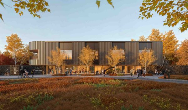 Exterior building entrance with signage, people, and fall leaves on trees