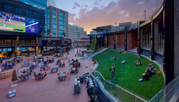 Outdoor courtyard with seating, grass area, and screens for watching the game