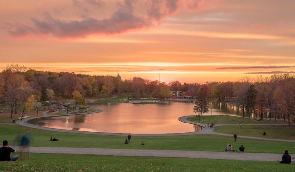 View of the lake with people sitting on grass around it