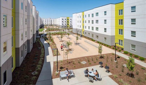 View of outdoor courtyard between buildings with outdoor seating and bike racks.