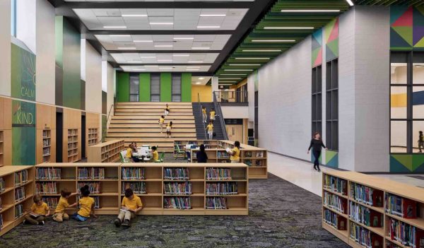 Students in an open library area with a large staircase in the background.