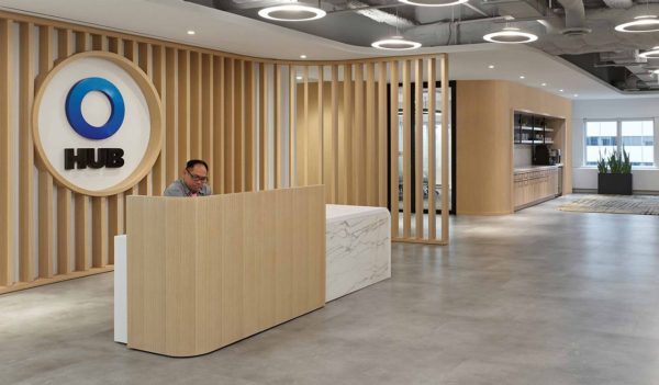 Interior main reception area with vertial wood slat feature wall behind  a wood and marble reception desk.